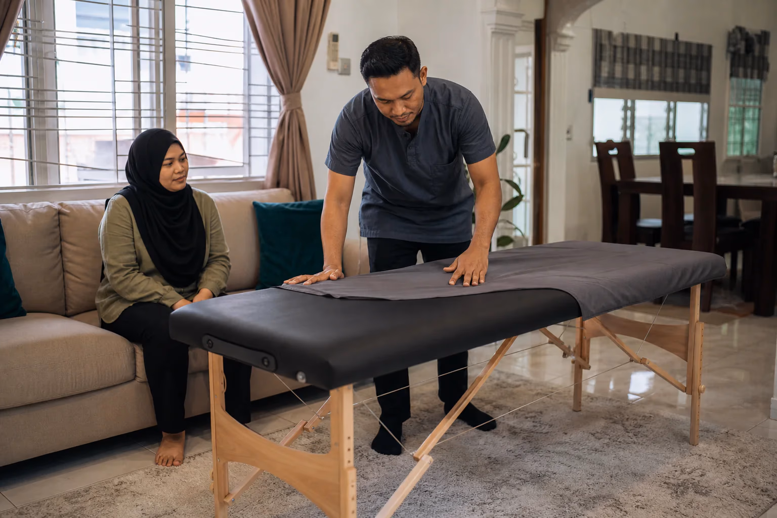 Ahli terapi menyediakan katil rawatan di rumah pelanggan Melayu
