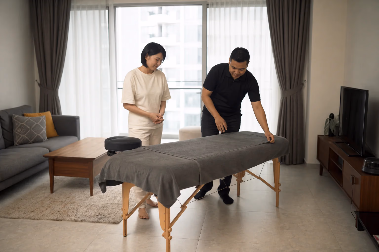 A therapist preparing a treatment bed in a Chinese Malaysian home